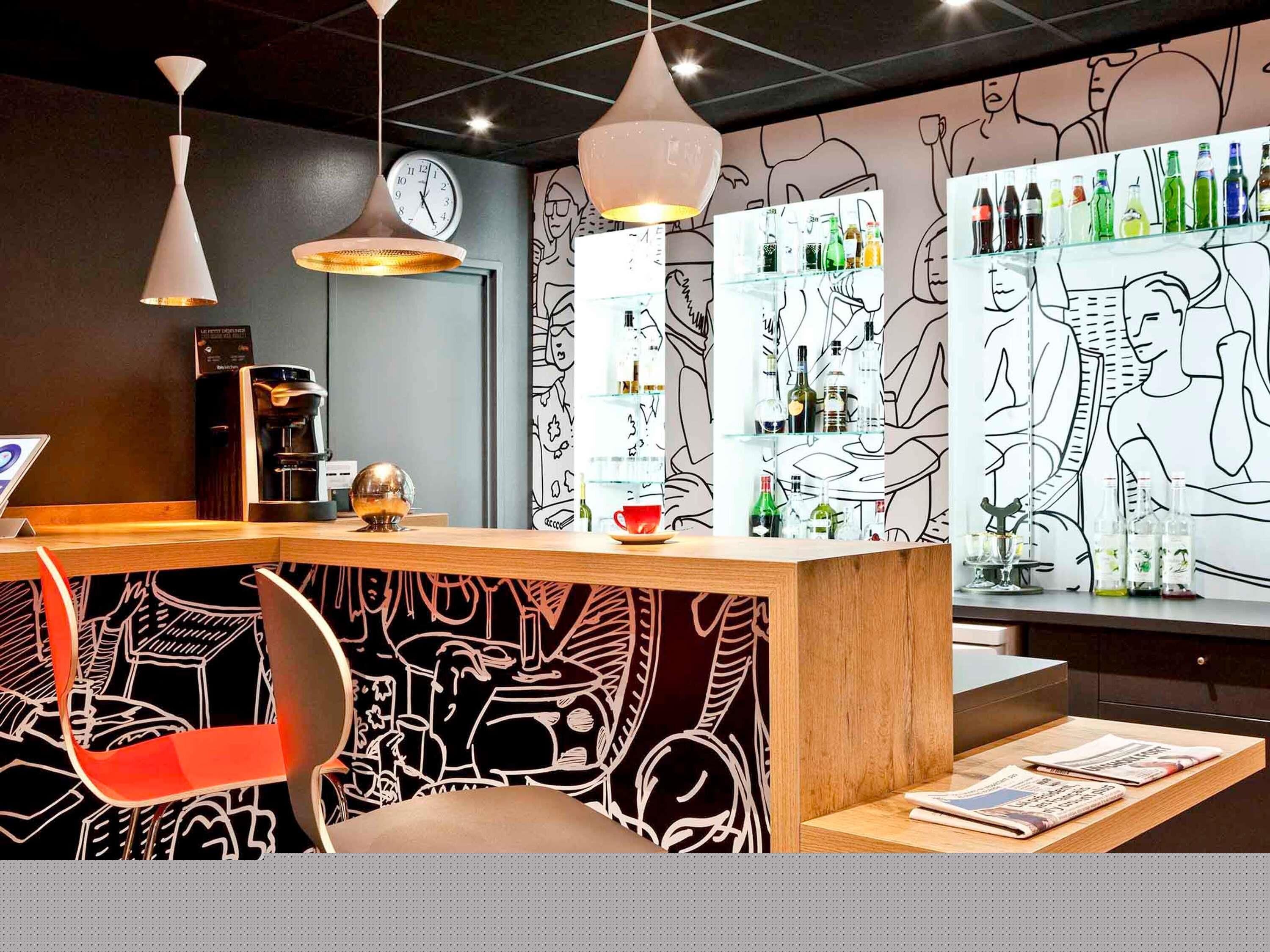 Una zona de bar con mostrador, asientos y una pared con arte abstracto en líneas.