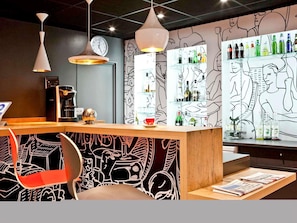 Een bar met een toonbank, zitplaatsen en een muur met abstracte lijntjes.