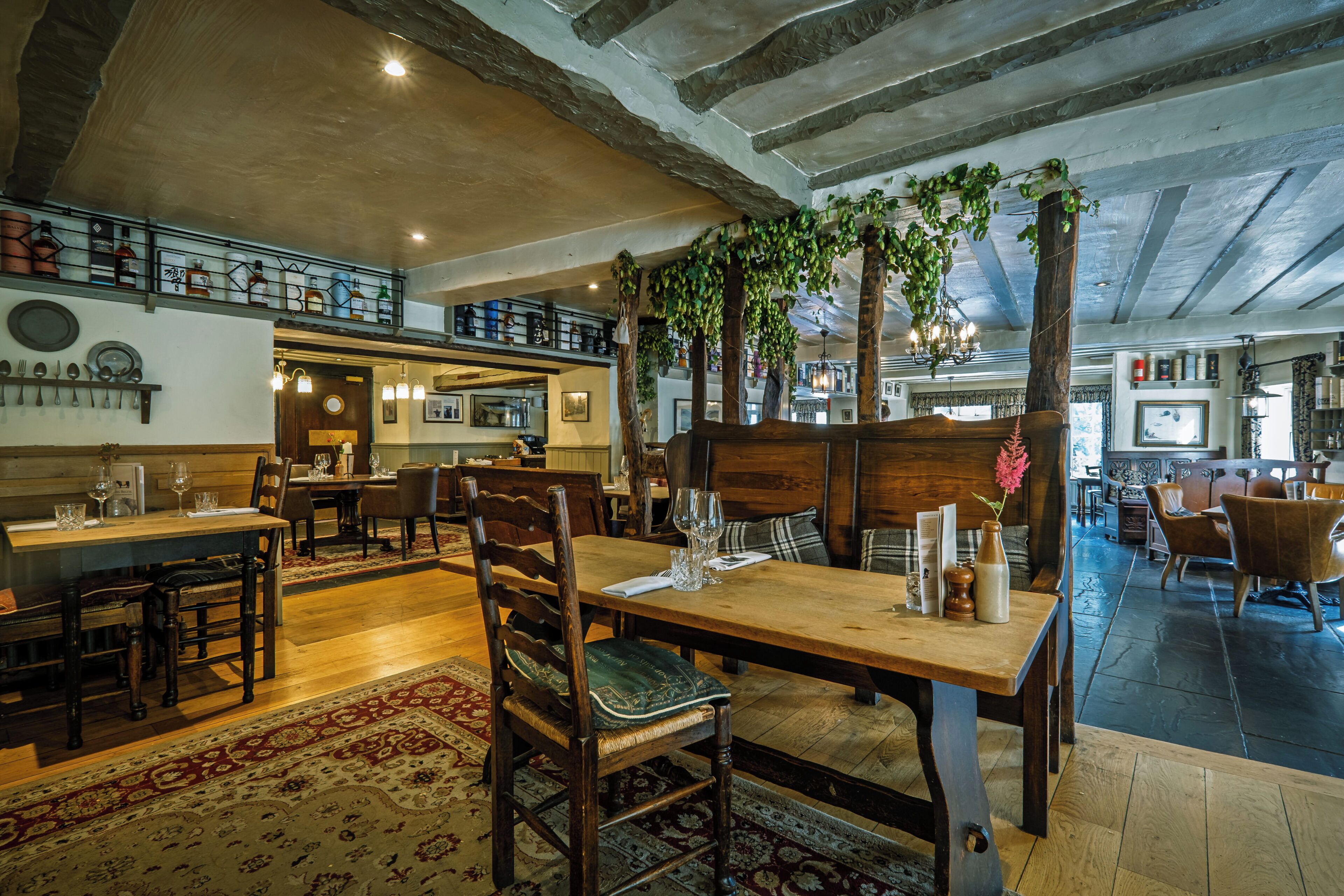 Un interior de restaurante con mesas y sillas de madera, y un techo alto con vigas a la vista.