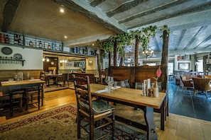 Un interior de restaurante con mesas y sillas de madera, y un techo alto con vigas a la vista.