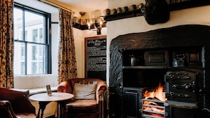 Un cuarto acogedor con chimenea, un sofá de cuero, una mesa y un ventanal con cortinas.