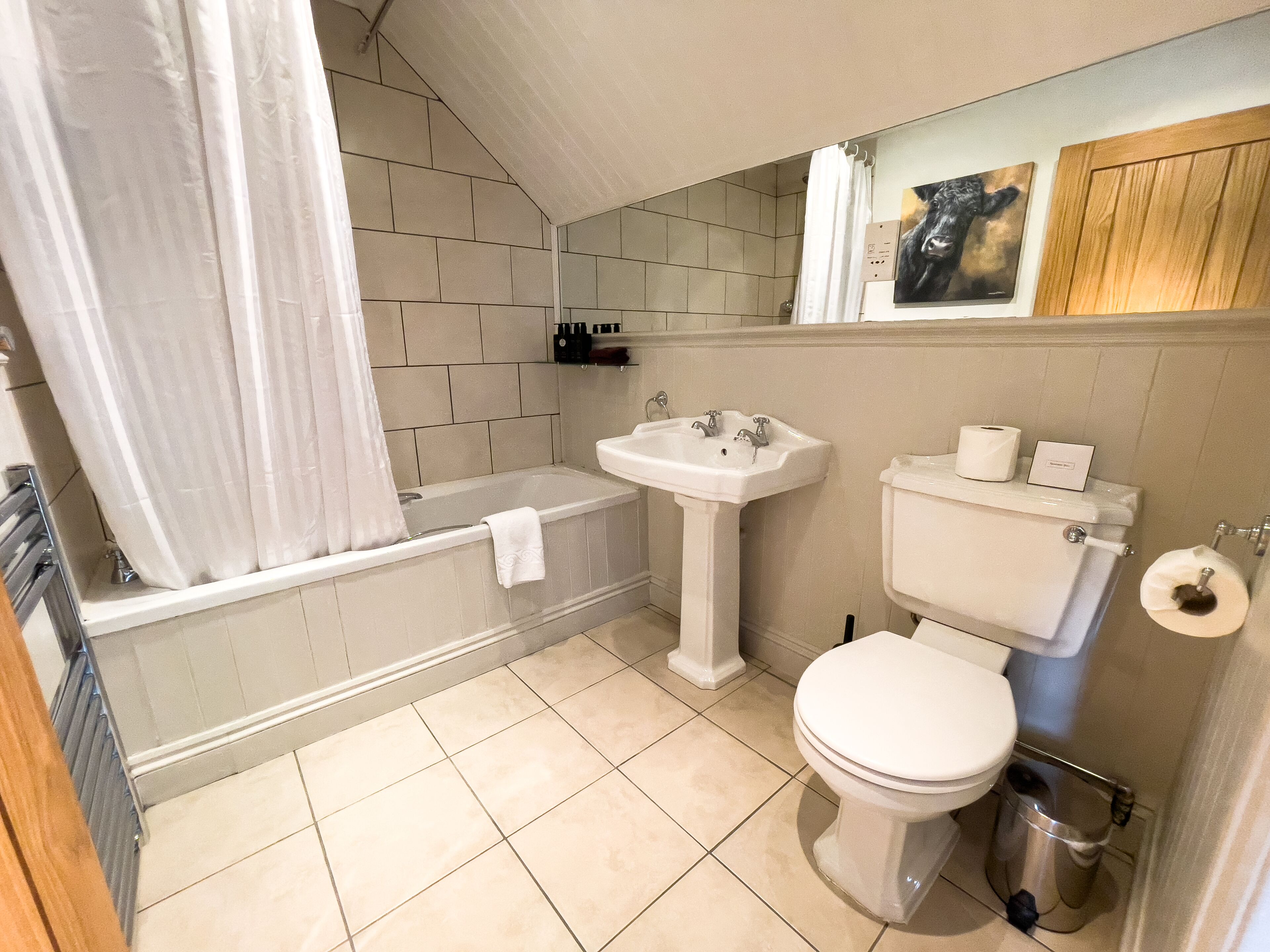 Een badkamer met een bad, wastafel, toilet en een prullenbak.