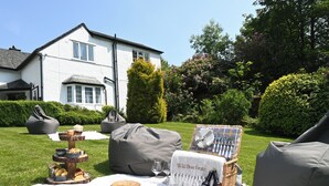 An outdoor dining setup with a picnic table, bean bags, and a basket of food items. - Wild Boar Estate (Windermere)