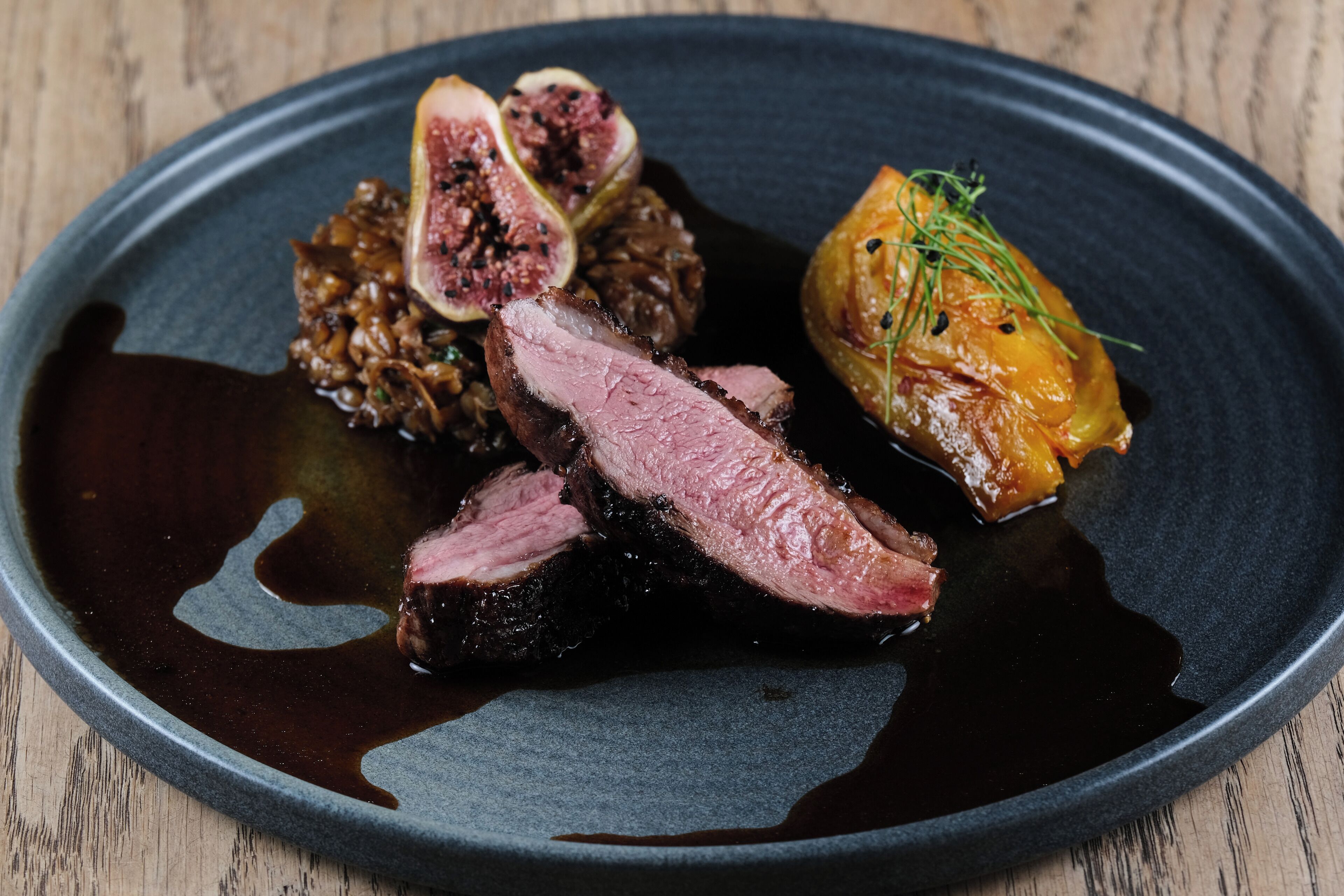 A plate with sliced meat, figs, and a roasted vegetable.