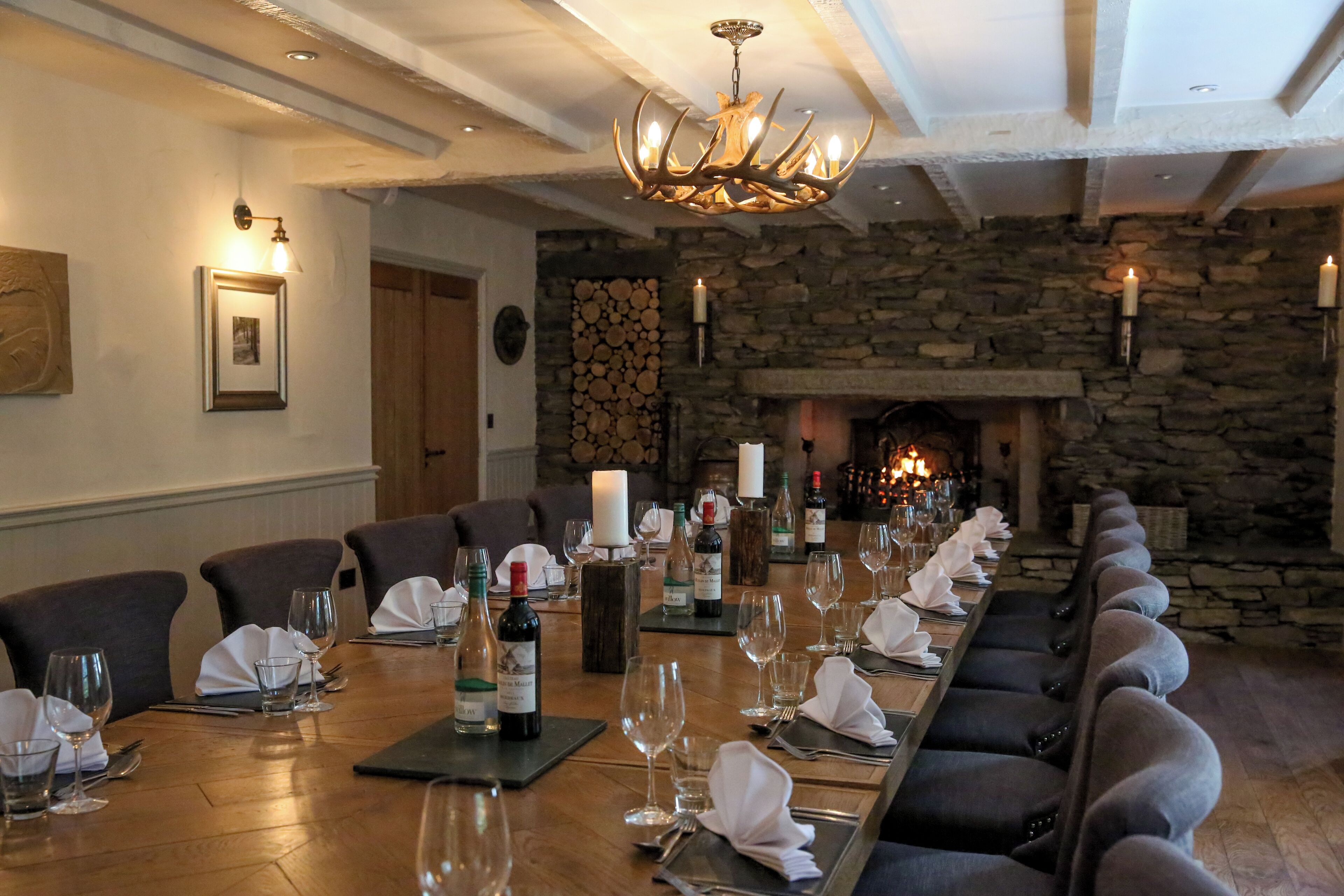 A long dining table set for a meal with wine bottles, glasses, and plates.