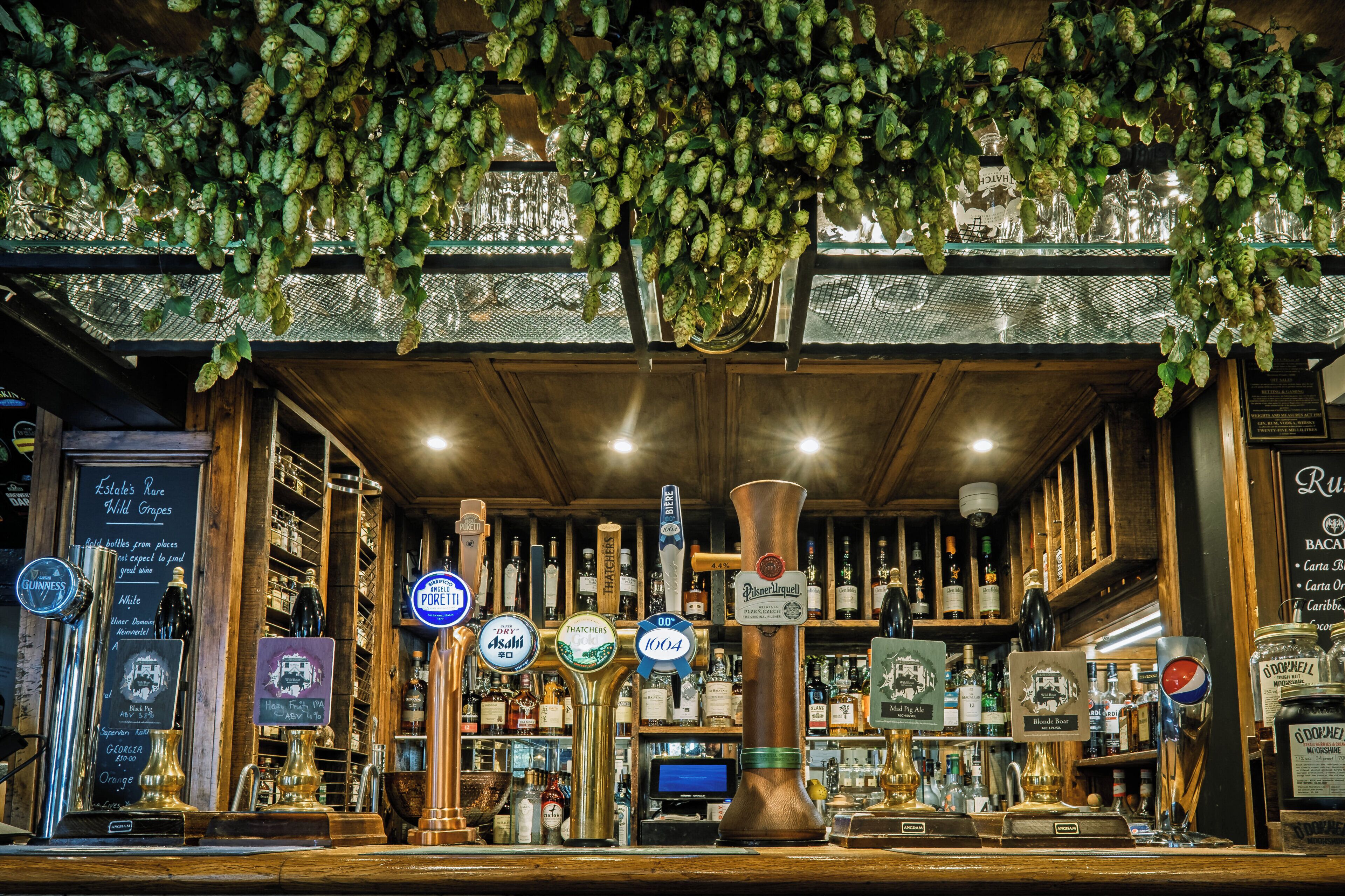 Un bar con varias opciones de grifos y botellas de cerveza, un menú en pizarra y una decoración rústica.