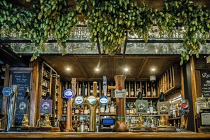 Un bar con varias opciones de grifos y botellas de cerveza, un menú en pizarra y una decoración rústica.