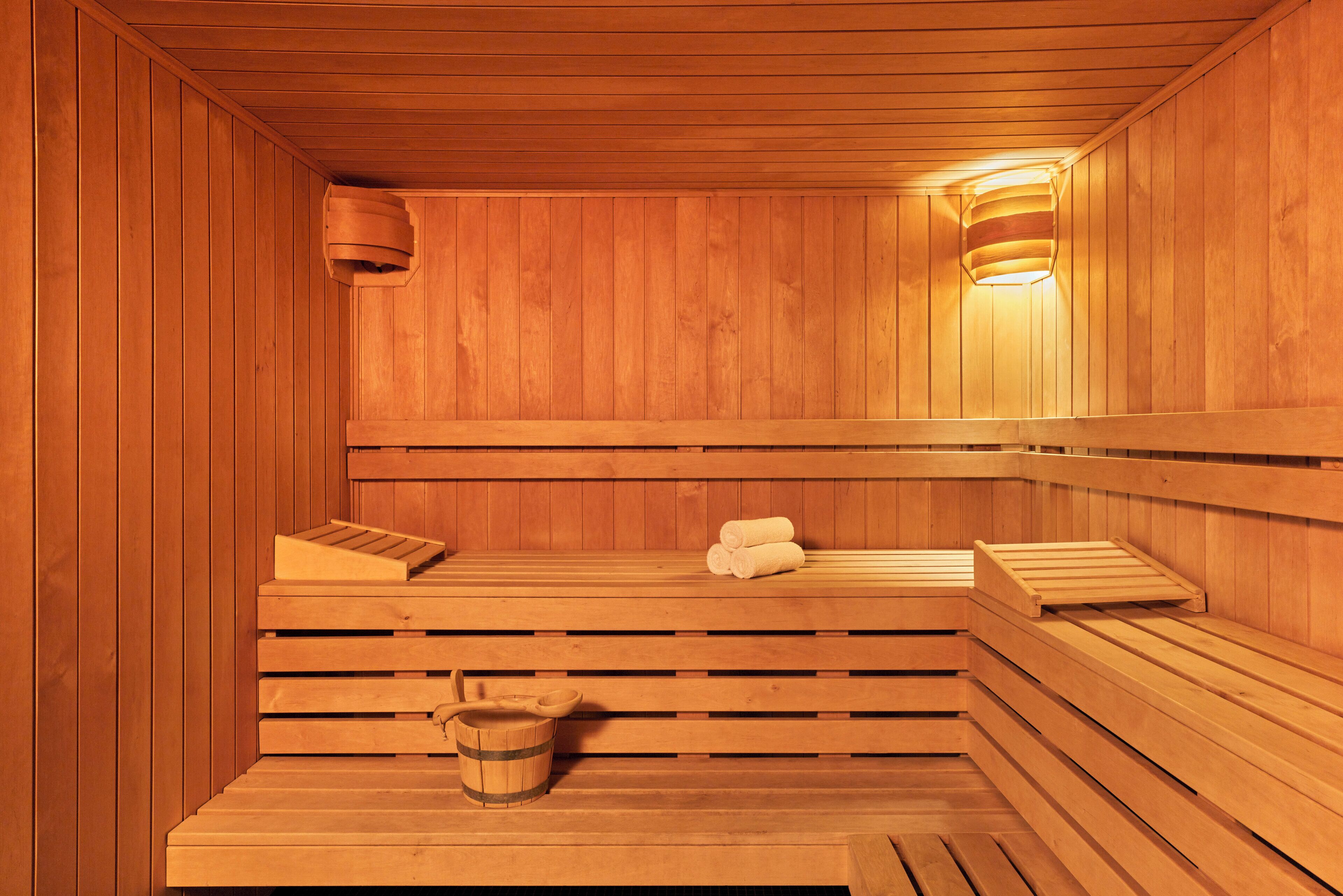 Eine Holzsauna mit Bänken, einem Eimer und Handtüchern.