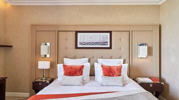 A hotel room with a large bed, two nightstands, a framed picture on the headboard, and a red throw blanket.