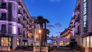 Un hotel elegante con varios pisos, grandes ventanales y una entrada bien iluminada.