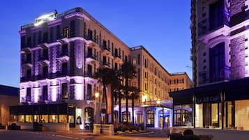 Un hotel imponente de estilo arquitectónico clásico, con varios balcones y una fachada bien iluminada.