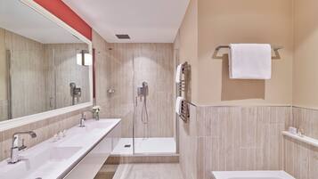 A modern bathroom with two sinks, a shower, and a bathtub.