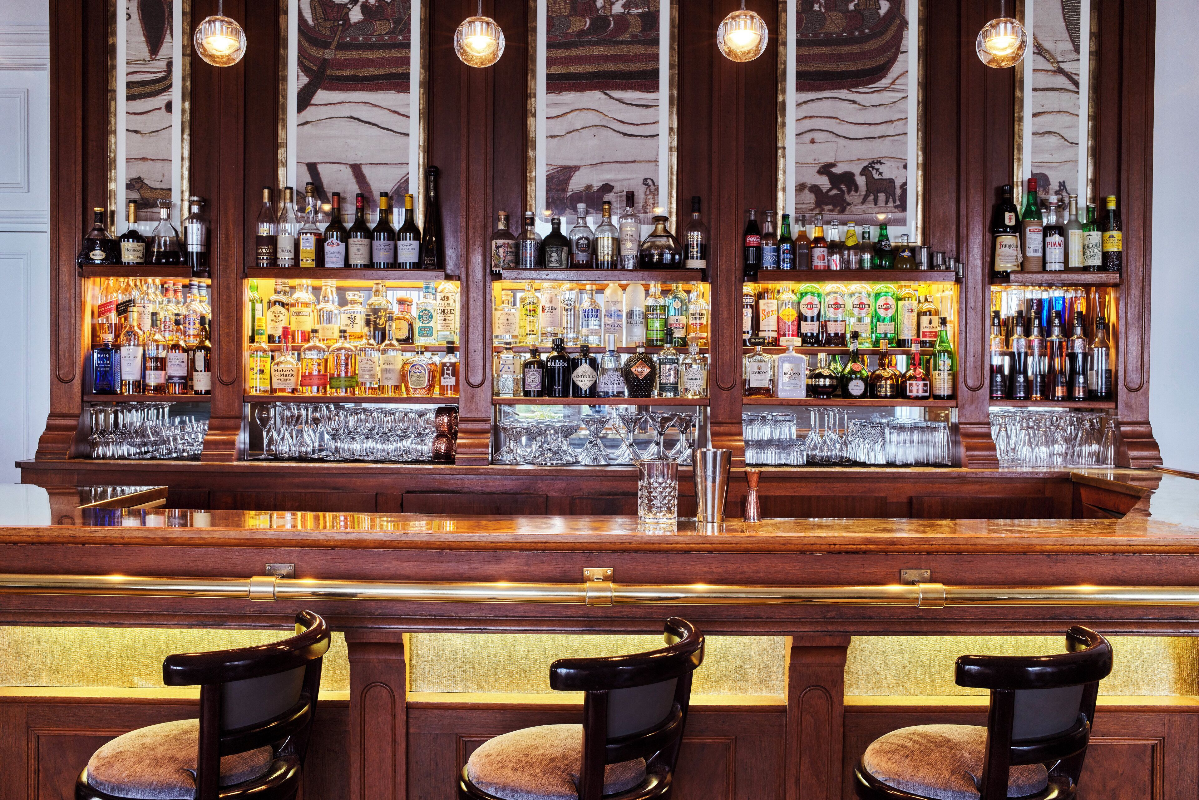 A bar with multiple shelves of liquor bottles, glasses, and a wooden counter.