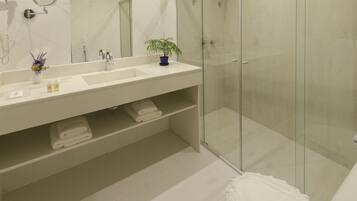 Un bagno moderno con box doccia in vetro, un mobile lavabo bianco con specchio e una pianta in vaso.