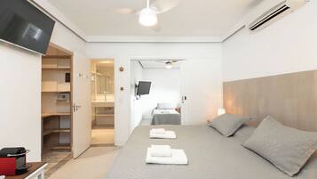 Une chambre d’hôtel moderne équipée d’un lit, d’une télévision, d’un ventilateur de plafond et d’un dressing.