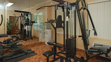 A gym with various exercise machines, a water cooler, and a mirror on the wall.