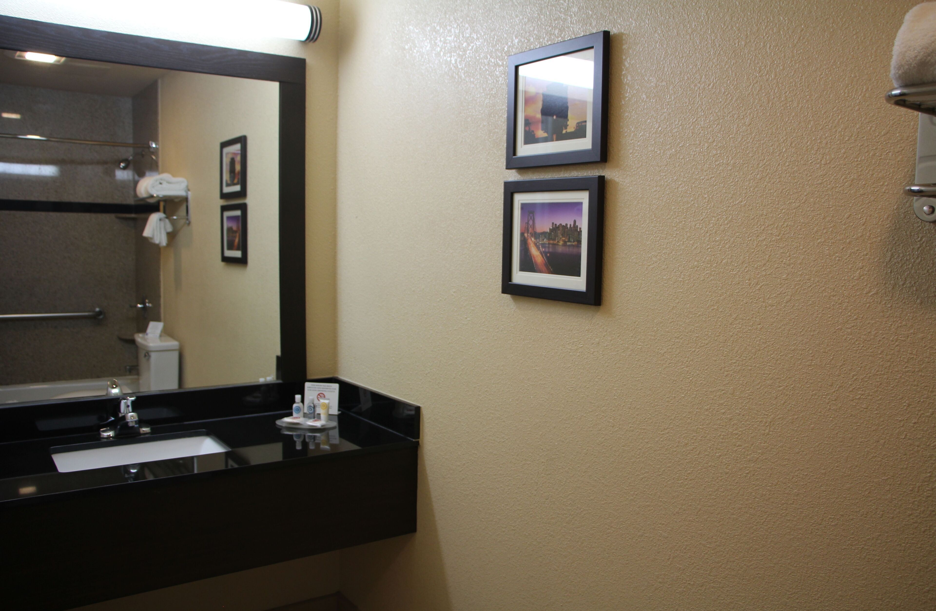 A bathroom with a black sink, a mirror, and two framed pictures on the wall.