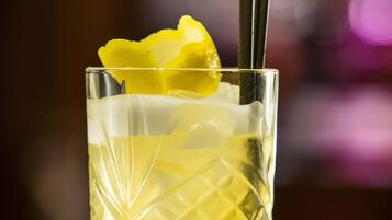 A clear glass with a textured pattern, containing a yellow beverage, a lemon slice, and two straws.