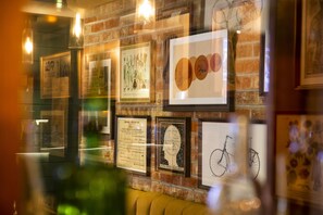 A wall with various framed artworks and a brick wall. - JA The Bruntsfield - Edinburgh (Edinburgh)
