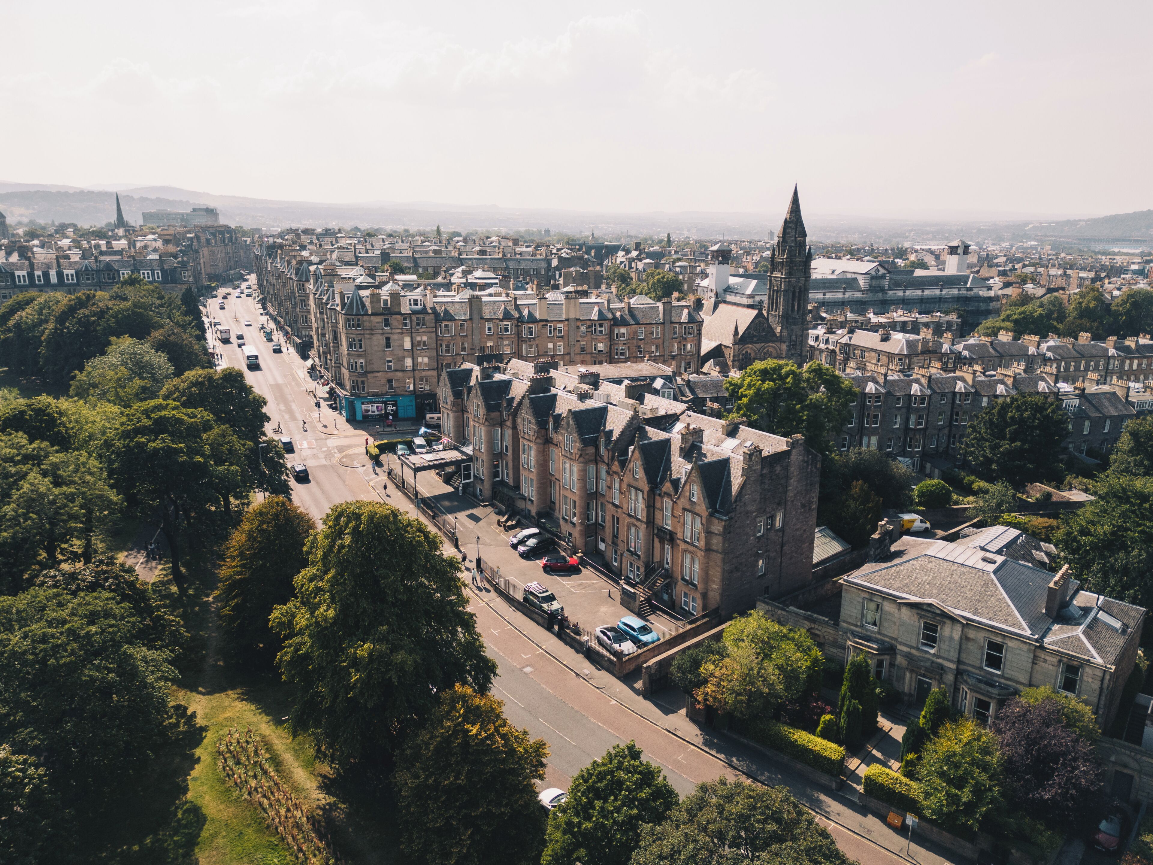 An aerial view of a cityscape with historic buildings, a prominent church spire, and a busy street.
