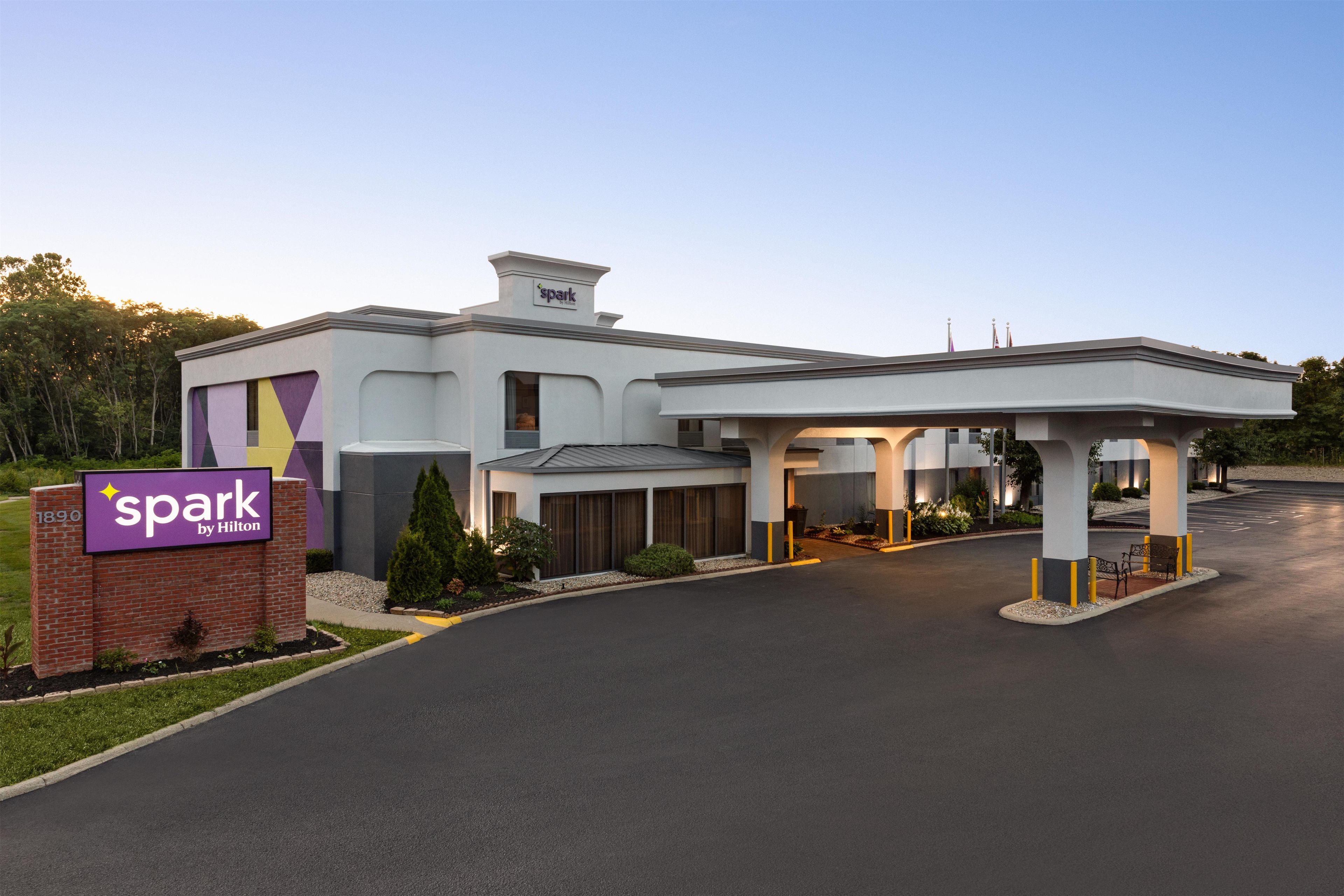 A hotel with a modern design, a parking lot, and a landscaped entrance area.