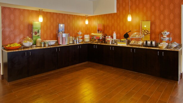 A spacious kitchen with wooden cabinets, a granite countertop, and various food items and appliances.