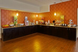 Uma cozinha ampla com armários de madeira, bancada de granito e diversos alimentos e eletrodomésticos.