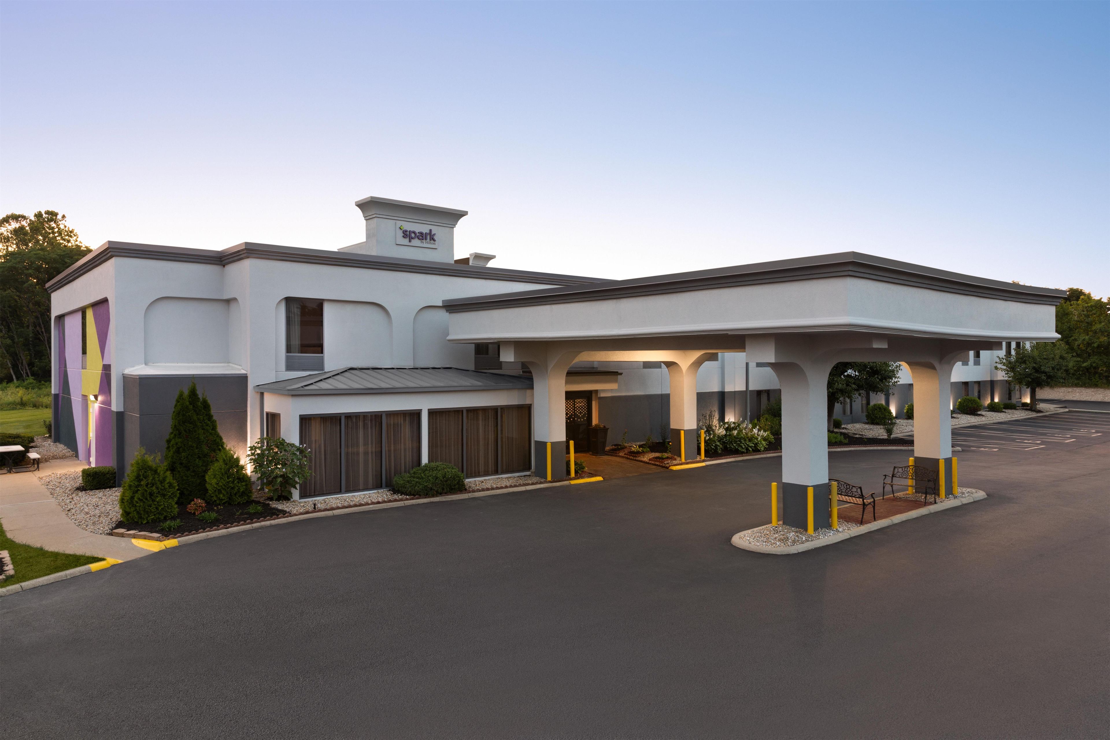 A modern hotel with a covered entrance and a parking lot.