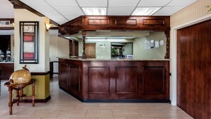 Un espace d’accueil avec un comptoir en bois, un globe terrestre posé sur une petite table et des certificats encadrés accrochés au mur.