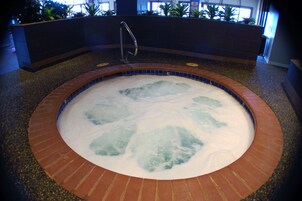 Un jacuzzi con borde de azulejos y grifo metálico.