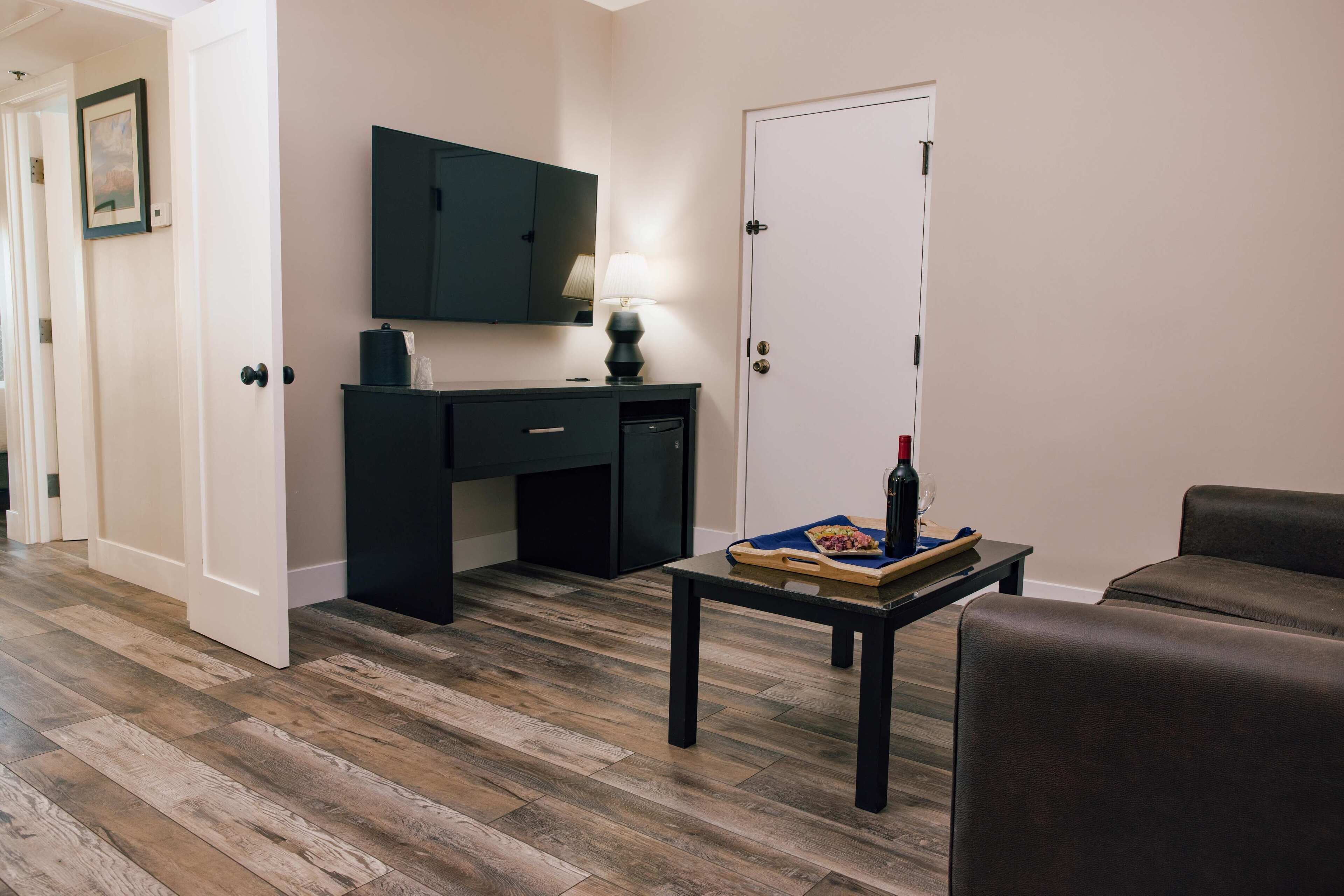 Ein Zimmer mit Holzboden, Schreibtisch mit Lampe, Stuhl und Sofa.