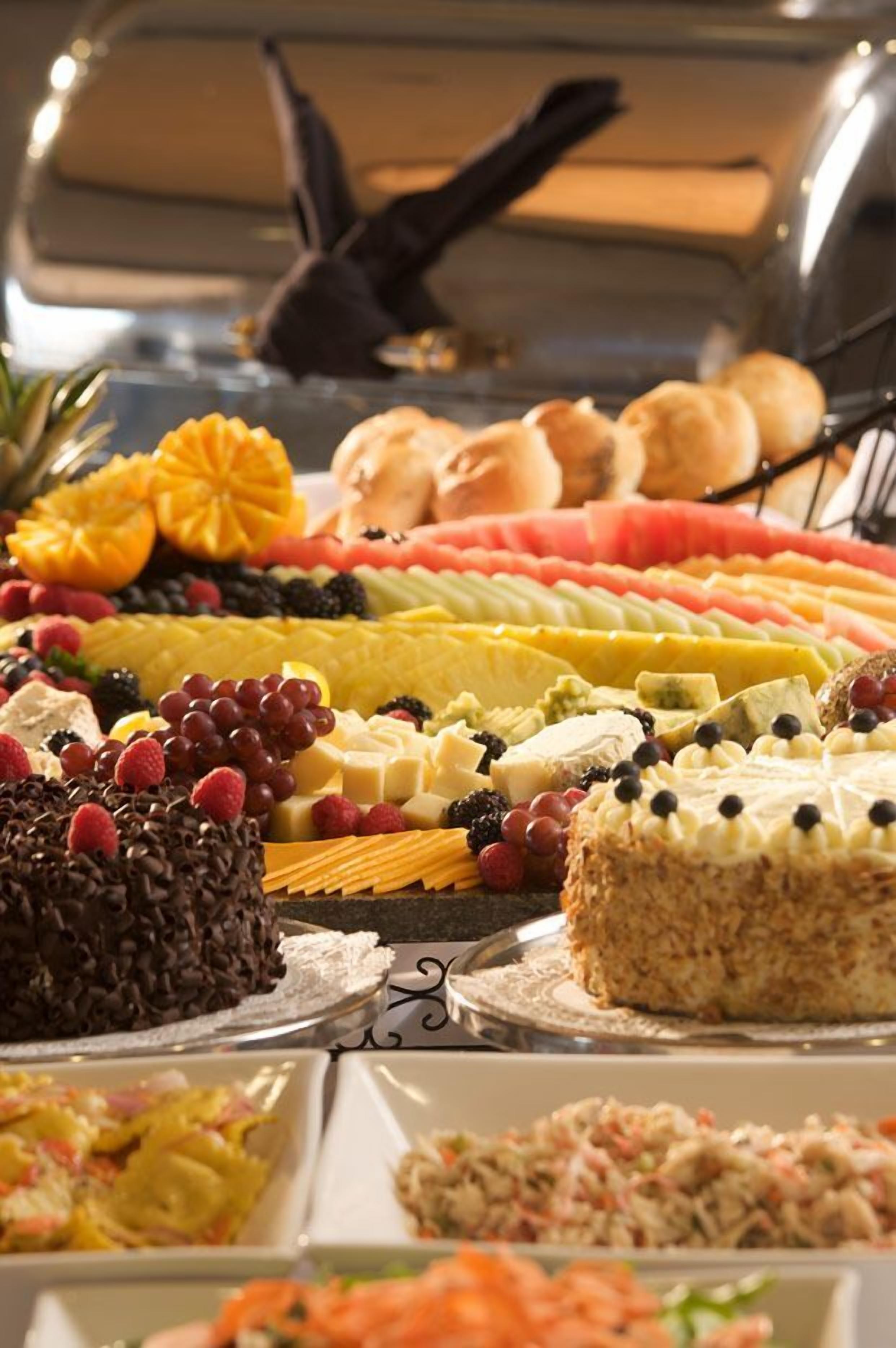 A buffet with various food items including fruits, cakes, and pastries.