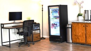A room with a desk, chair, computer, refrigerator, trash can, and a cabinet. - Travelodge by Wyndham Trinidad (Trinidad)