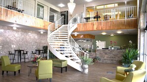 A spacious lobby with a central spiral staircase, multiple seating areas, and a reception desk. - Travelodge by Wyndham Trinidad (Trinidad)