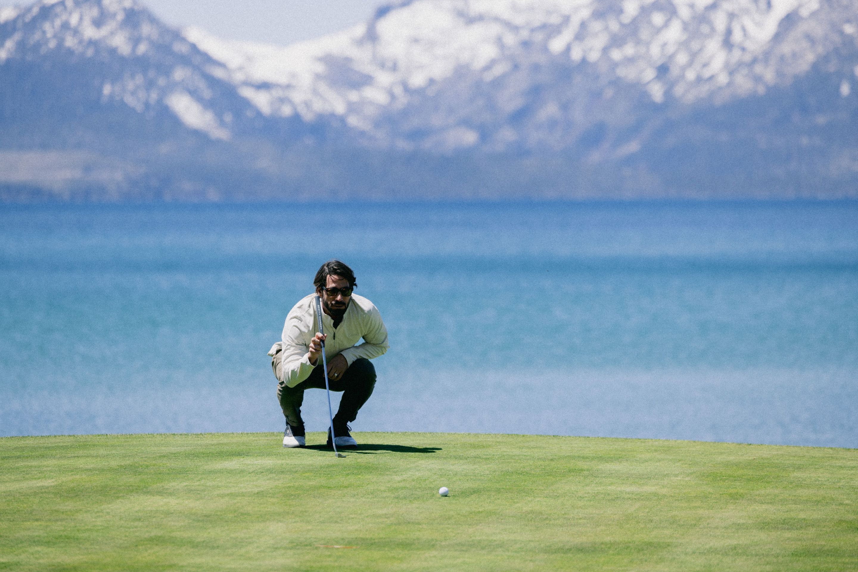 A person on a golf course with a mountainous backdrop.