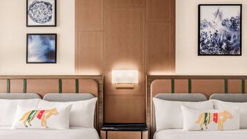 Habitación de hotel con dos camas, una mesita de noche y obras de arte colgadas en la pared.