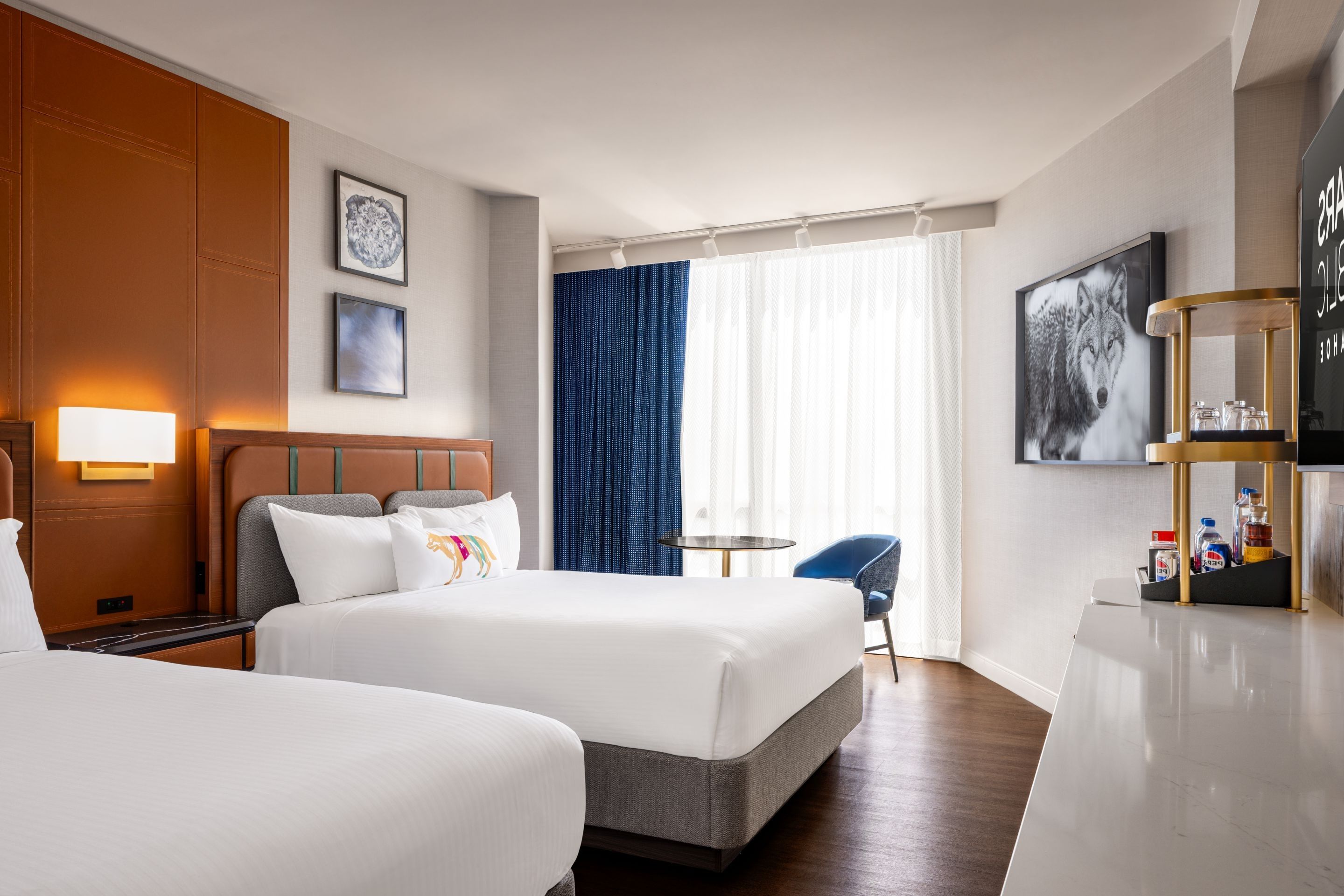 Habitación de hotel con dos camas, un escritorio, una silla y un televisor.