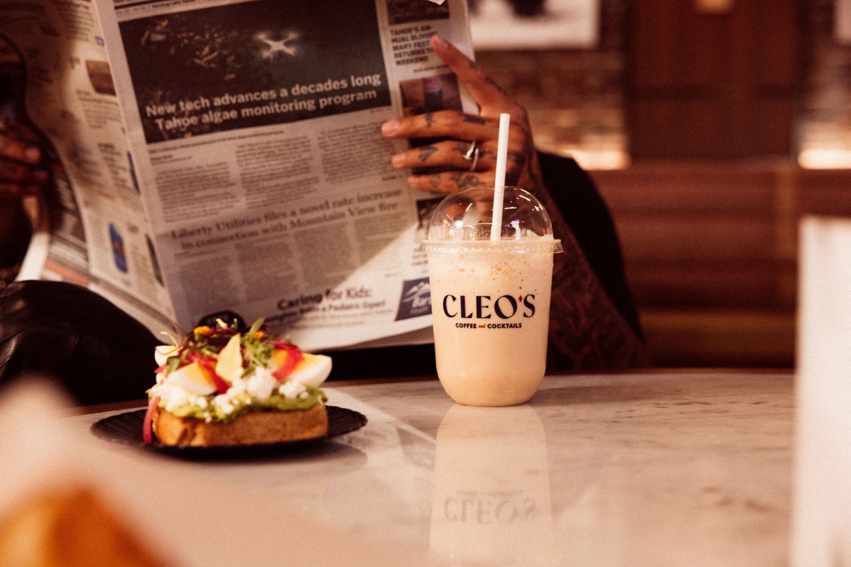 A beverage in a branded cup and a sandwich on a table.