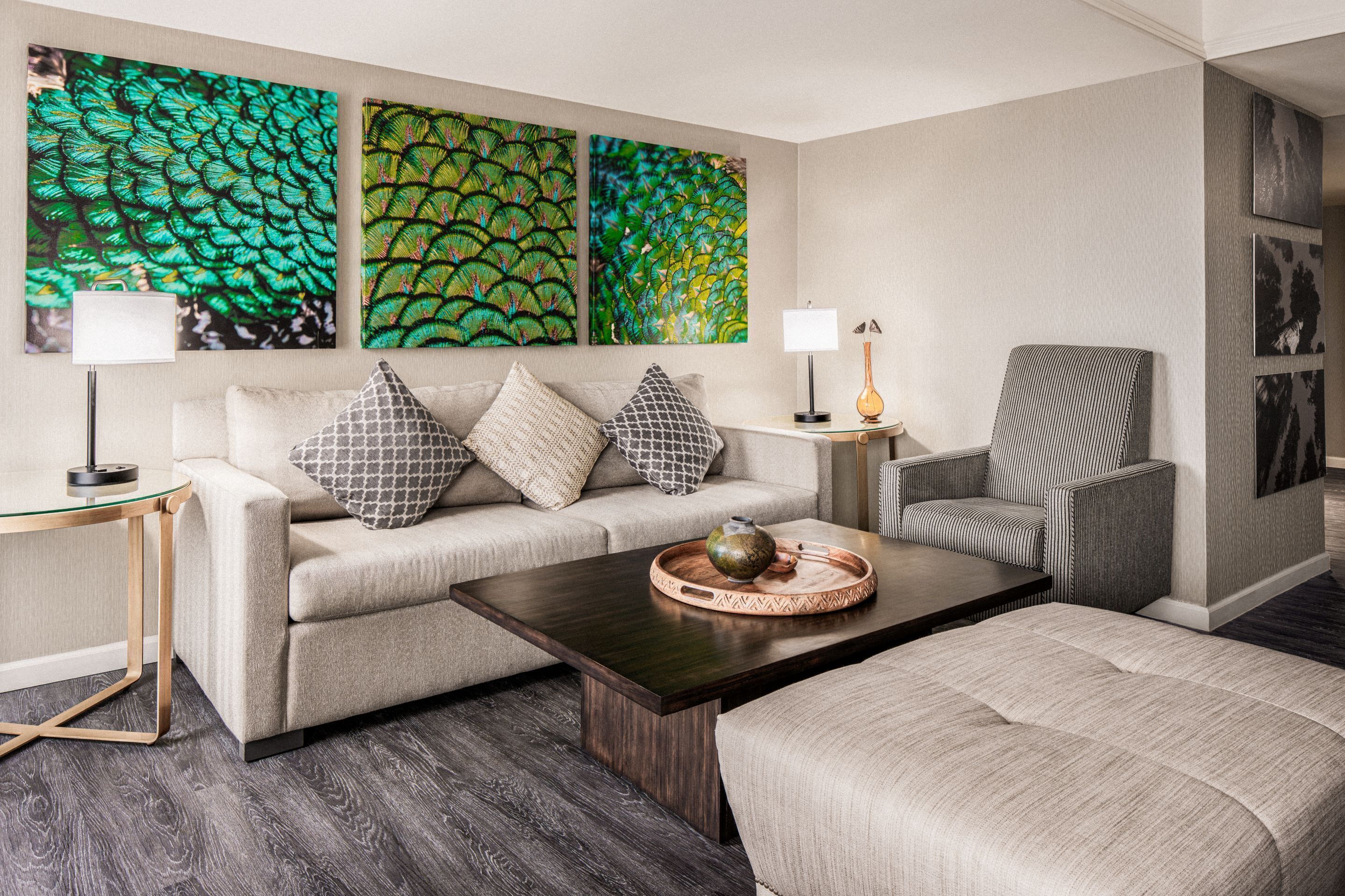 A modern living room with a sofa, armchair, coffee table, and artwork on the wall.