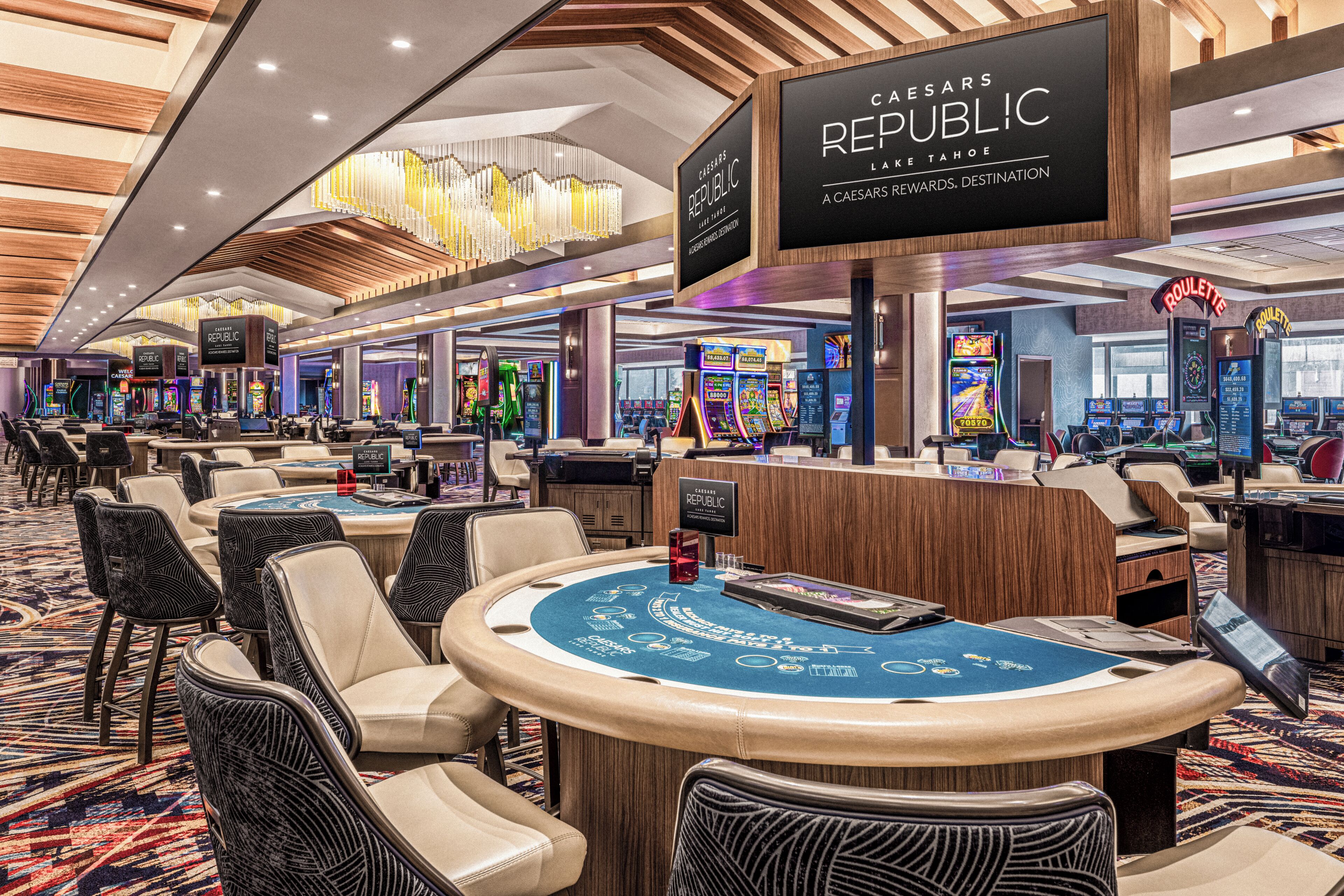 Un casino Caesars Republic con varias mesas de blackjack, máquinas tragamonedas y una gran lámpara de cristal.