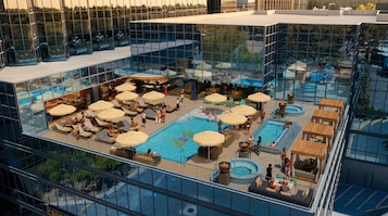 A rooftop pool area with sun loungers, umbrellas, and a bar.