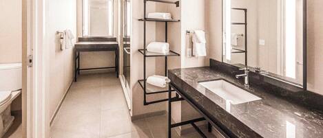 A modern bathroom with a black marble sink, a large mirror, and a towel rack.