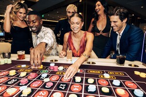 A group of people playing blackjack at a casino table.