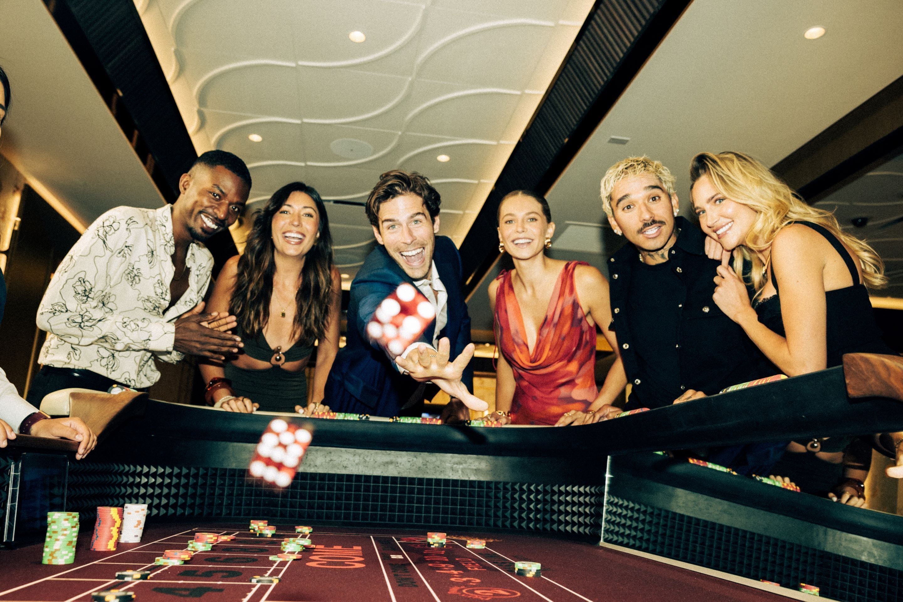 A group of people playing blackjack at a casino table with chips and cards.