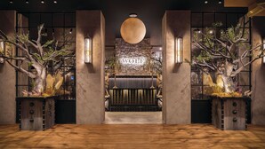 A reception area with a large wooden sign reading 'WOLF,' a stone wall, and two large trees with branches.