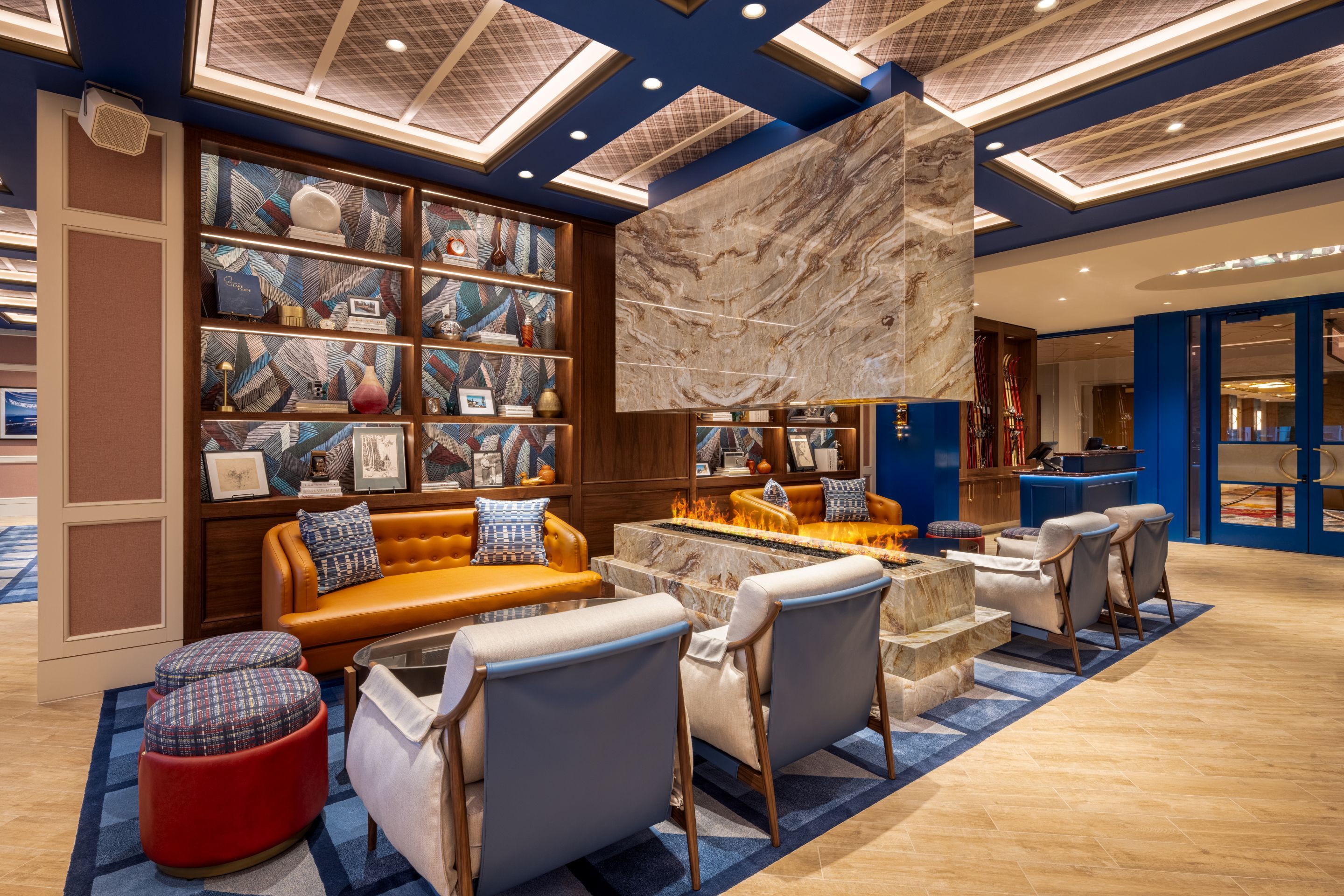 A modern lounge area with a fireplace, seating, and a large bookshelf.