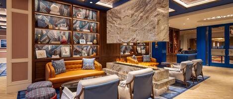A modern lounge area with a fireplace, seating, and a large bookshelf.
