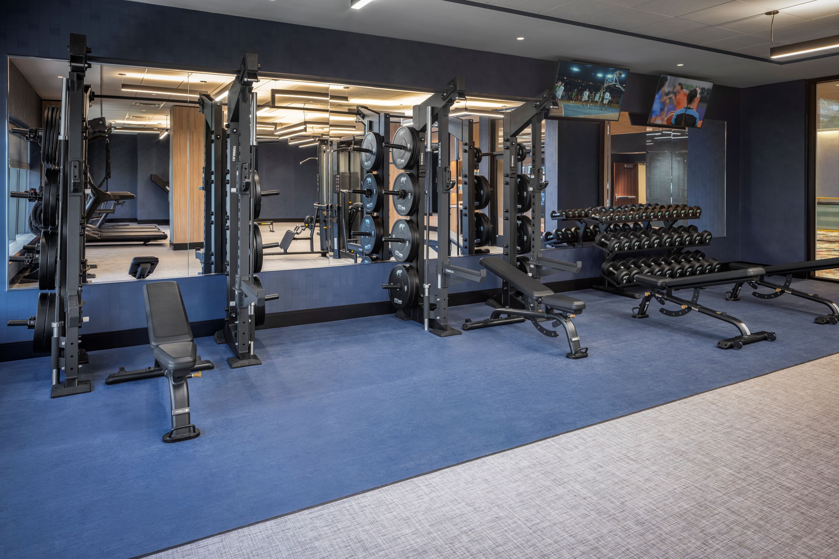 A gym with various exercise equipment, including weight machines, benches, and dumbbells.