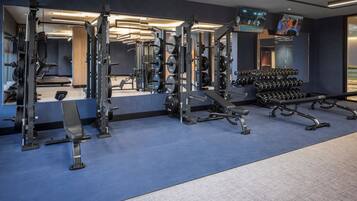 A gym with various exercise equipment, including weight machines, benches, and dumbbells.