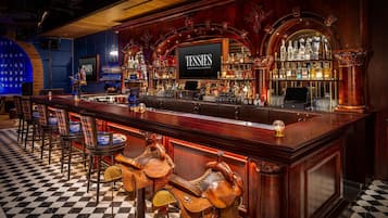 Un bar avec un sol à carreaux, des tabourets et une enseigne sur laquelle on peut lire : « TESTIES COCKTAILS & CHORDS ».